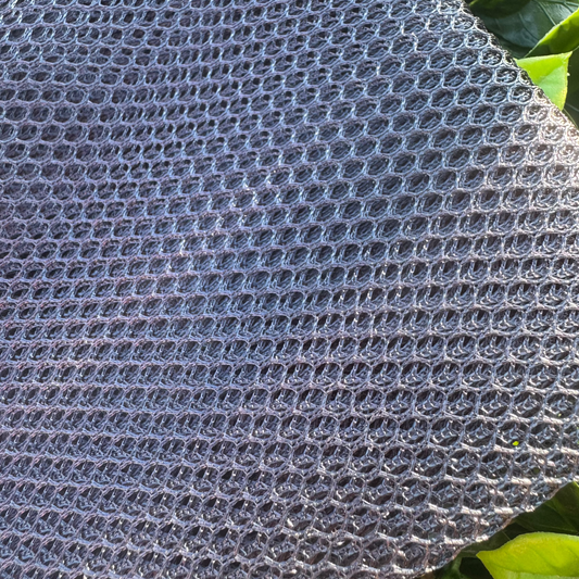 Textured gray material with green leaves in the background