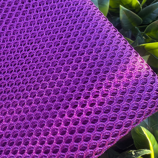 Close-up of a purple textured fabric with green leaves in the background