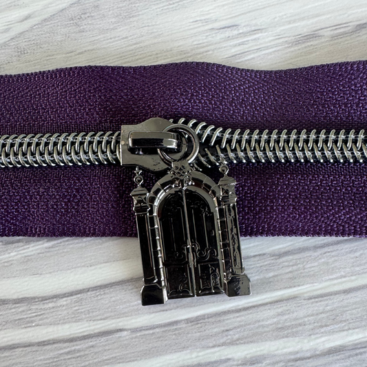 Decorative zipper pull on a purple zipper against a marble background