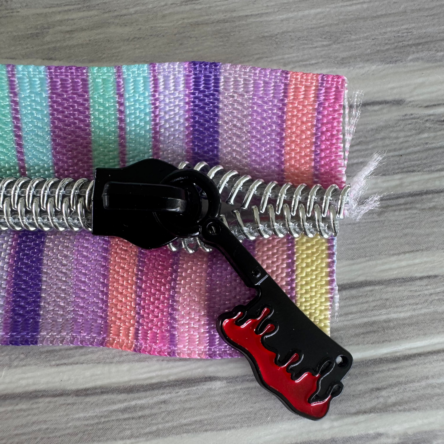 Black and red tool with a coiled hose on a striped fabric background