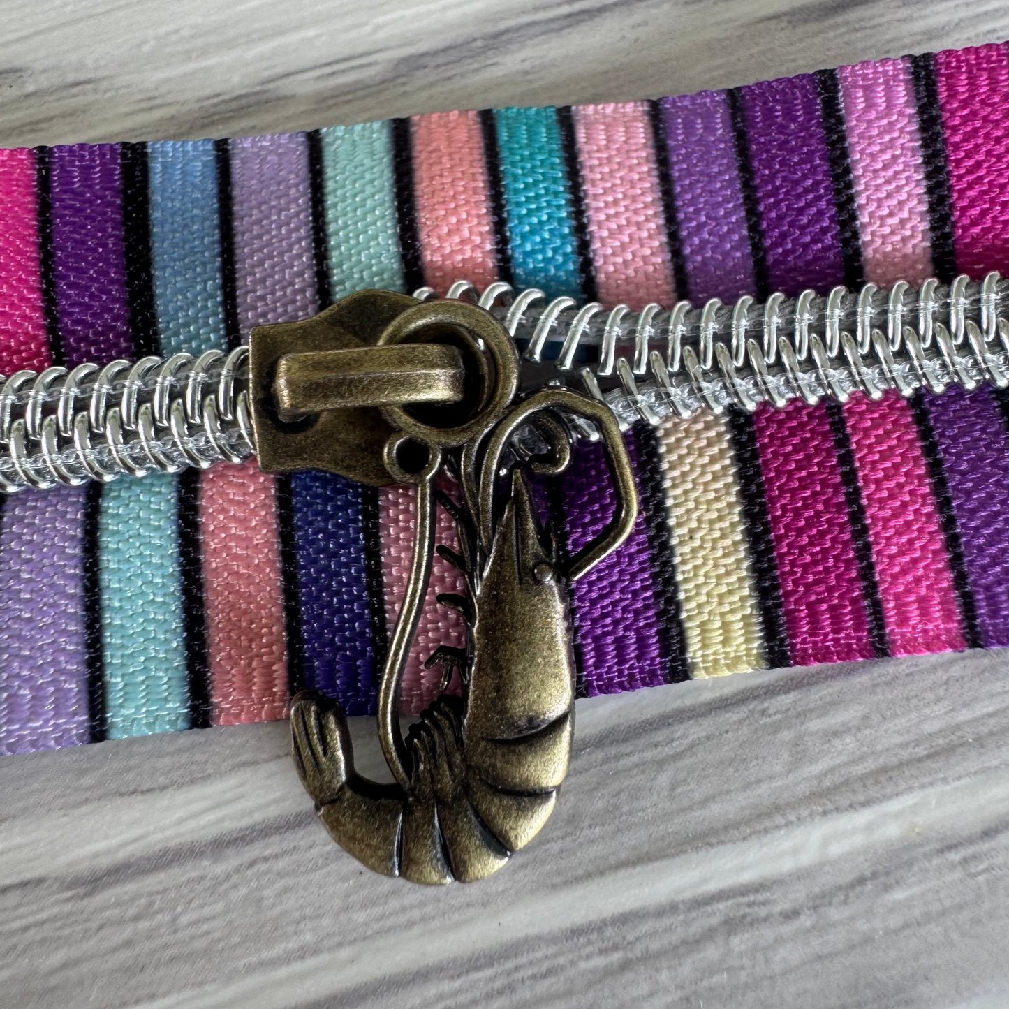 Close-up of a zipper with a decorative pull on a striped fabric background